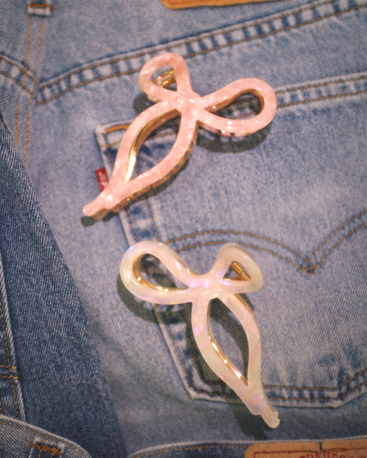 Pink bow-shaped hair clips on a denim background