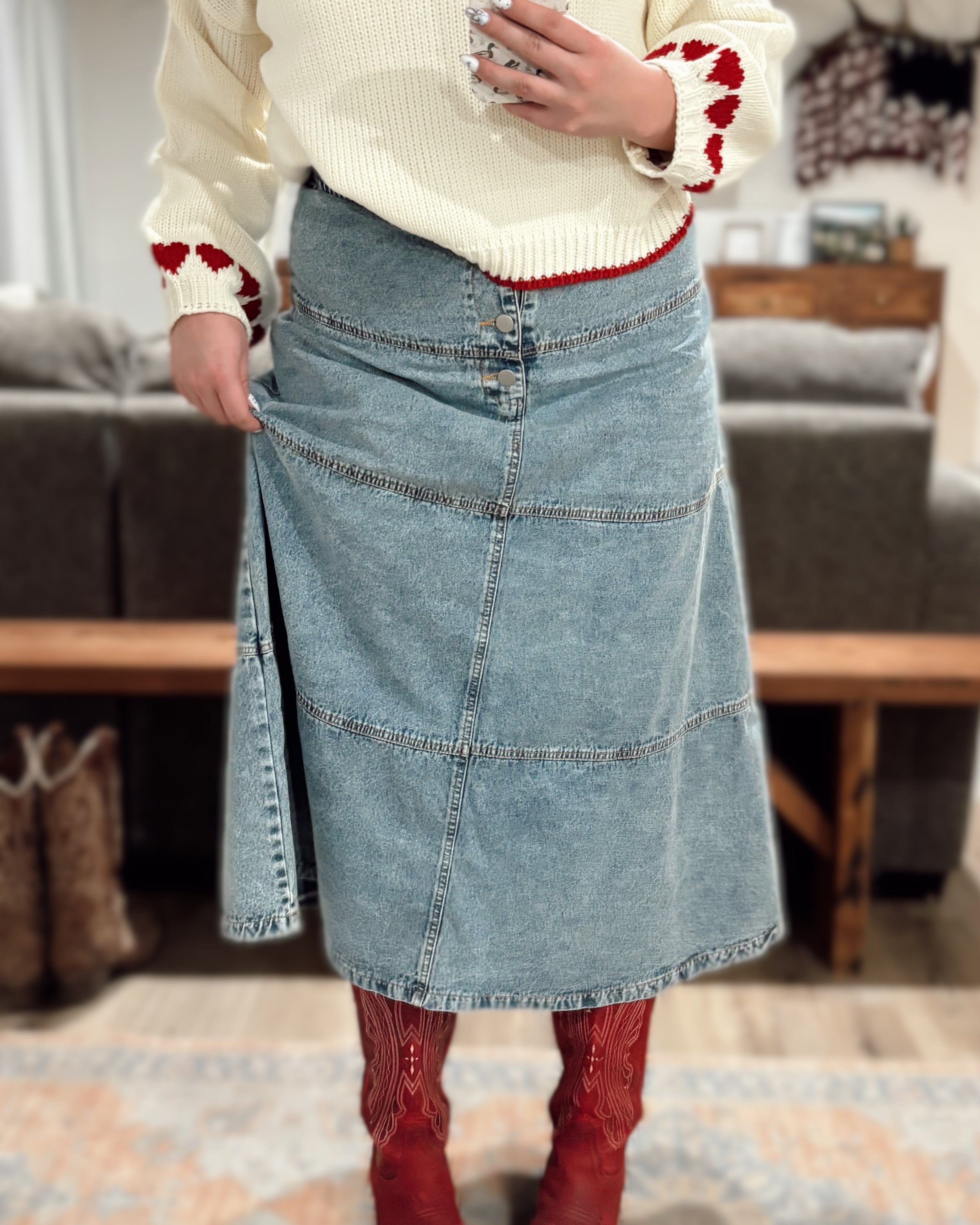 Person wearing a cream sweater with red accents, blue denim skirt, and red boots.