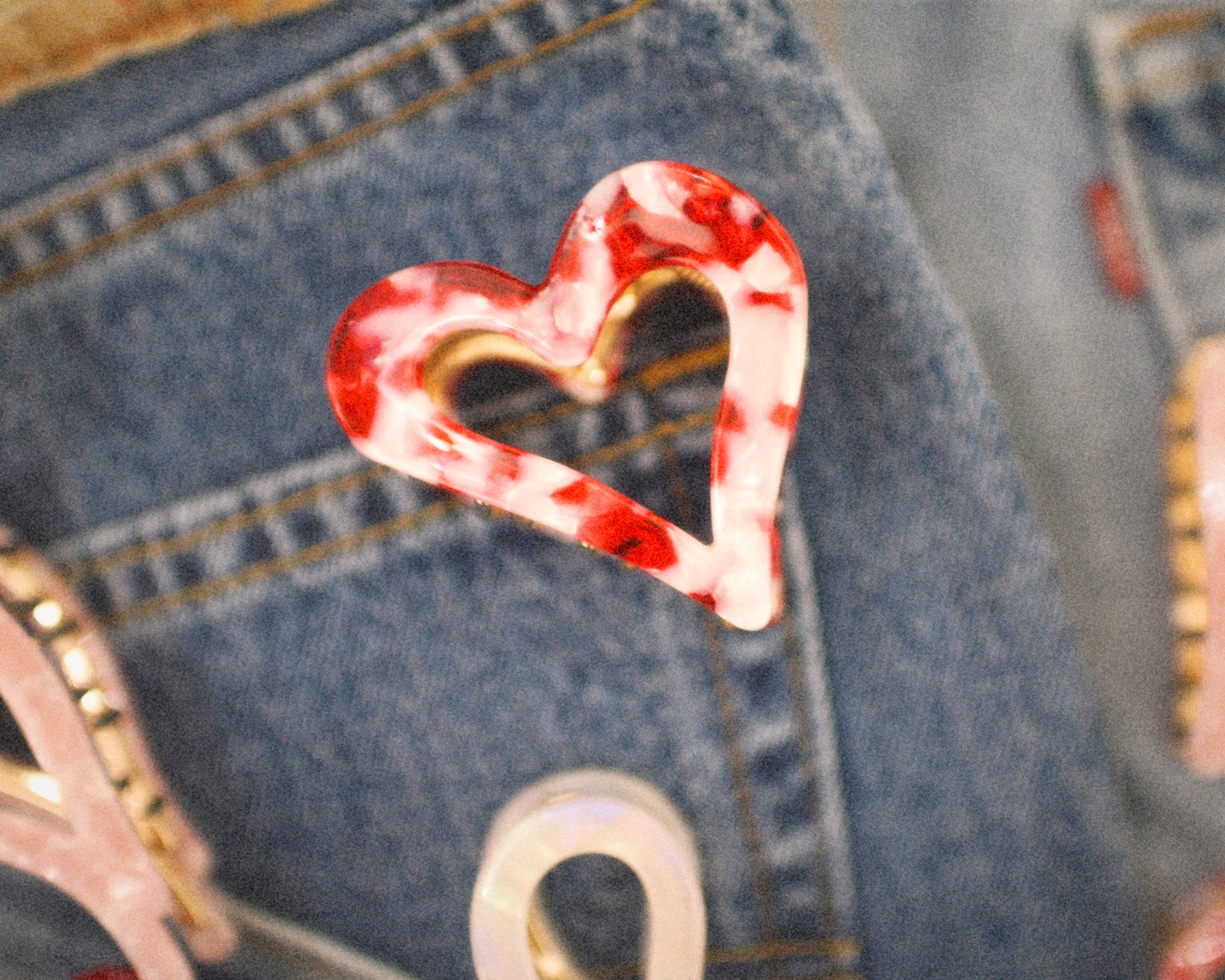 Red and white heart-shaped hair clip on a denim background